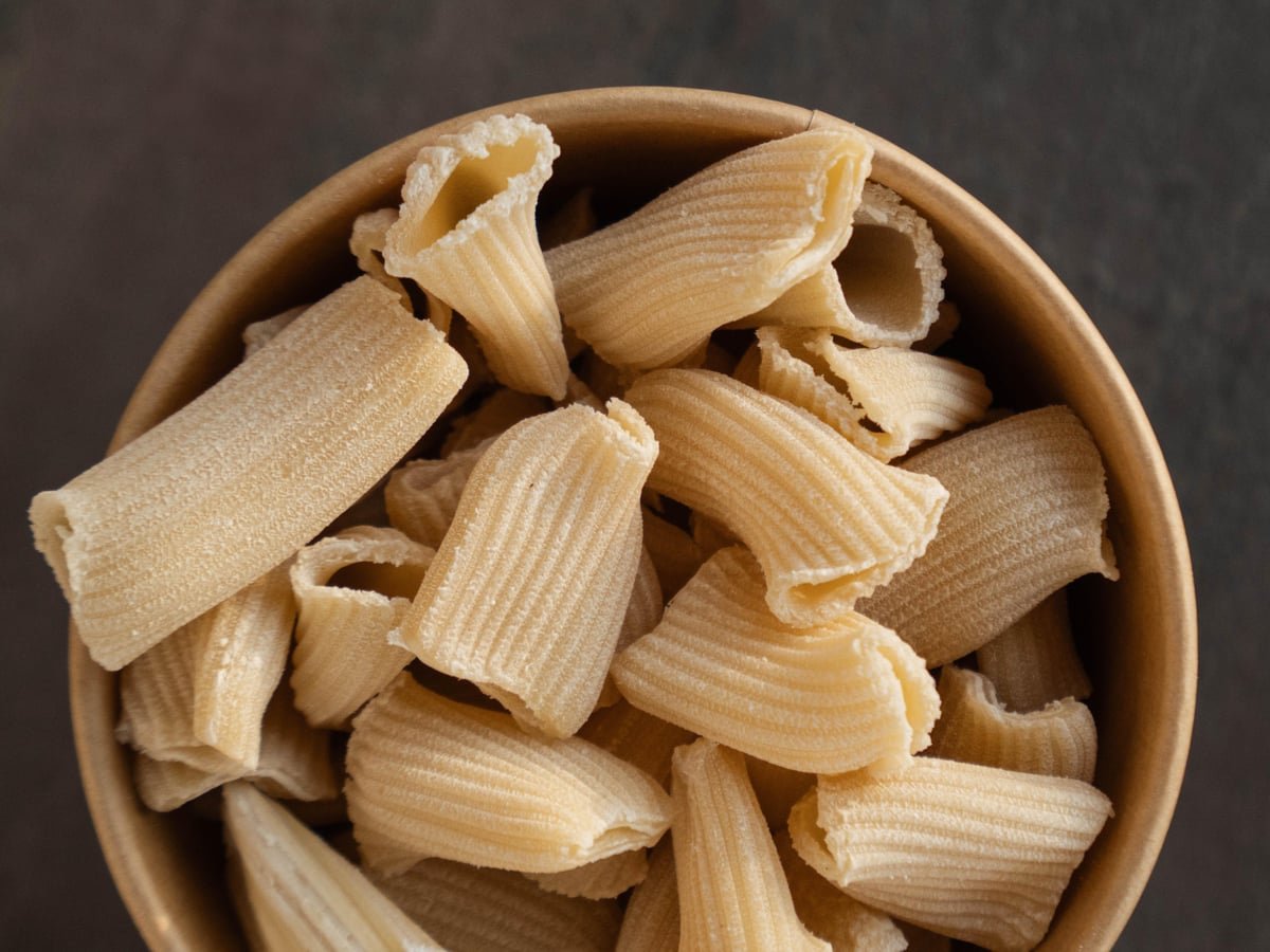 Rigatoni — bronze-die ridged tubes in a wooden bowl